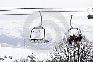 People On A Chairlift Ascend A Ski Slope photo