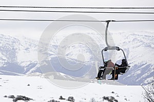 People On A Chairlift Ascend A Ski Slope photo