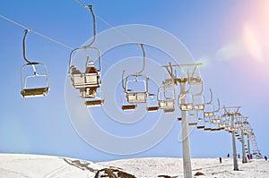 People in a chairlift in a ski resort in winter with scenic lens flare