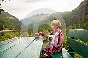 People, children enjoying the amazing views in Norway to fjords, mountains and beautiful nature miracles, having breakfast while