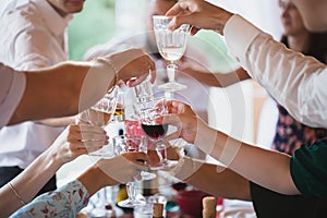 People clang glasses sitting at dinner table in sparkling lights.