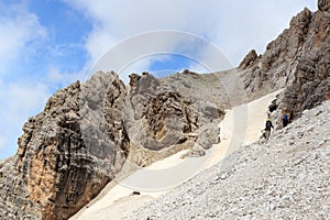 People climbing the Via Ferrata Severino Casara and snow field in Sexten Dolomites mountains, South Tyrol