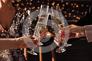 People clinking glasses of champagne indoors, closeup