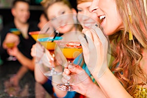 People in club or bar drinking cocktails