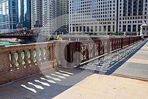 People commute during morning rush hour amongst shadow patterns created on the surface of the Chicago River bridge