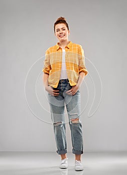 Red haired teenage girl in shirt and torn jeans