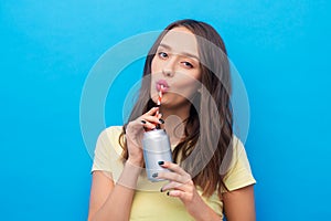 Young woman or teenage girl drinking soda from can photo