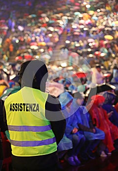 People during a concert and a boy with jacket with text ASSISTEN