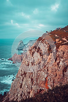 People contempating the ocean from a high cliff
