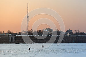 People crossing of frozen Neva river in St. Petersburg at sunset in winter