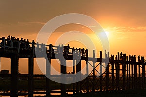 People crossing the longest teak bridge in the world, the iconic wooden U Bein Bridge during sunset, Mandalay, Myanmar