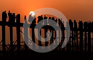 People crossing the longest teak bridge in the world, the iconic wooden U Bein Bridge during sunset, Mandalay, Myanmar