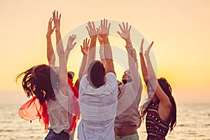 People dancing at the beach with hands up. concept about party, music and people photo