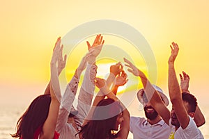 People dancing at the beach with hands up. concept about party, music and people photo