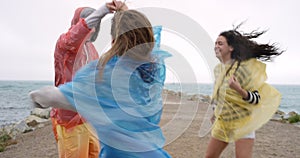 People, dancing in rain and beach celebration for holiday, winter vacation and party, freedom or energy. Young group of