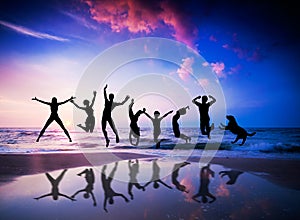 People and dog jumping on beach