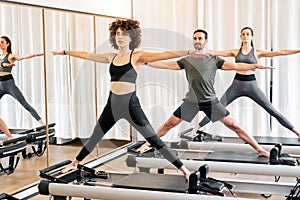 People doing pilates standing pose on reformer beds in gym