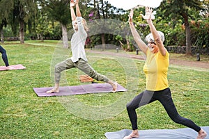 People doing yoga class outdoor at city park - Main focus on senior woman face