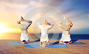 People doing yoga headstand on mat outdoors
