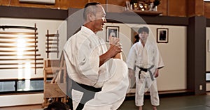 People in dojo with sensei for aikido training, fitness and challenge with gym, exercise and coaching. Teaching