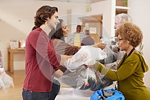 People Donating Clothing To Charity Collection In Community Center