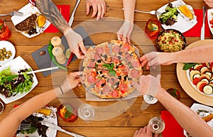 People eat pizza at festive table dinner party