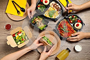 People eating healthy meals at wooden table. Food delivery