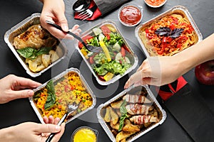 People eating from lunchboxes at grey table. Healthy food delivery