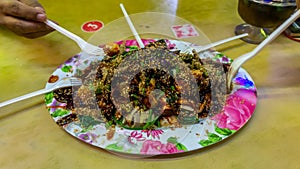 People eating Yong Tau Foo or Yentafu, a Chinese cuisine using plastic fork on a table