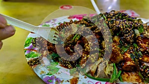 People eating Yong Tau Foo or Yentafu, a Chinese cuisine using plastic fork on a table