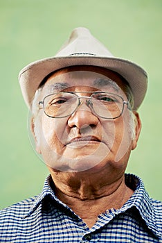 Portrait of serious old man with hat looking at camera