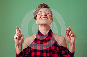 People and emotions -a portrait of smiling woman crosses fingers, prays about something, wishes luck, hopes in victory and