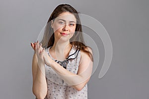 People and emotions. A young brunette in a blouse rubs her hands together in anticipation of success or profit. Copy space