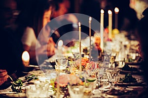 People enjoy a family dinner with candles. Big table served with food and beverages photo