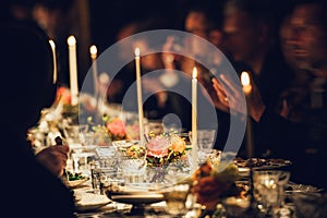 People enjoy a family dinner with candles. Big table served with food and beverages