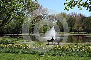 People enjoy spring at the pond with fountain in the Beatrixpark in Amsterdam