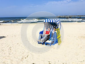 People enjoy sunbath in the roofed wicker beach chair