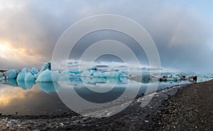 People enjoy the view of the icebergs floating in the water, blue ice reflects on the water