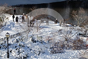 People Enjoying a Beautiful Winter Day at Central Park with Snow in New York City along the Pond