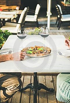 People enjoying fresh pizza and red wine in outdoor cafe