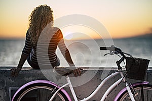 People enjoying outdoor leisure actvity looking a beautiful coloured sunset - woman with long curly blonde hair viewed from back