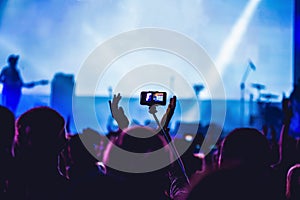 People enjoying rock concert and taking photos with cell phone a