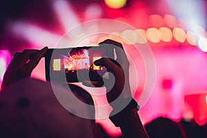 People enjoying rock concert and taking photos with cell phone a