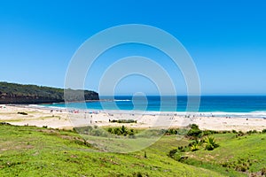 People enjoying the sunny weather at Pebbly Beach, a popular camping area with great surfing beach and bush walks within