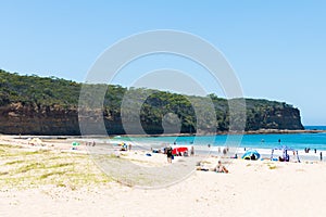 People enjoying the sunny weather at Pebbly Beach, a popular camping area with great surfing beach and bush walks within