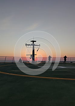 People enjoying sunset on the a helipad of a cruise ship