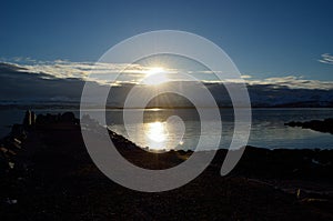 People enjoying the sunset over snowy mountain and calm fjord