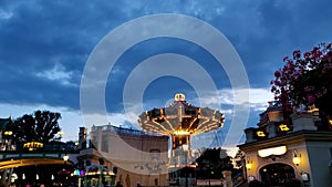 People are enjoying swinging rotation rides with friends and family in an amusement park during the evening in an European country