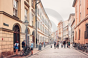 People walking and cycling on busy street in old  town Krakow.