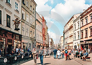 Couples and young families with children walking on busy street in old town Krakow.